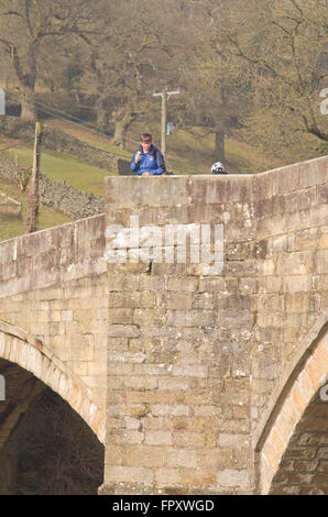 Frau auf der Suche über Brücke Brüstung Barden Bridge Bolton Abbey Yorkshire Dales Uk Stockfoto