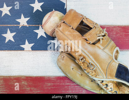 Alte abgenutzte Baseball Handschuh und Baseball auf verblasste Holztafeln gemalt rot, weiß und blau mit Flagge Muster. Stockfoto