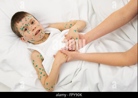 kranke Kind im Bett hat das Virus auf Haut, Mutters Hand berührt die Stirn Stockfoto