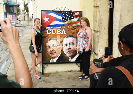 Havanna, Kuba. 20. März 2016. Menschen posieren für Fotos neben einem Zeichen in Alt-Havanna mit kubanischer Präsident Raul Castro und US-Präsident Barack Obama, Obama, Kuba am 20. März 2016 begrüßt. Obama der historischen Besuch, die heute beginnt, ist der erste von einer Sitzung US-Präsidenten in den 90er Jahren. (Paul Hennessy/Alamy) Stockfoto