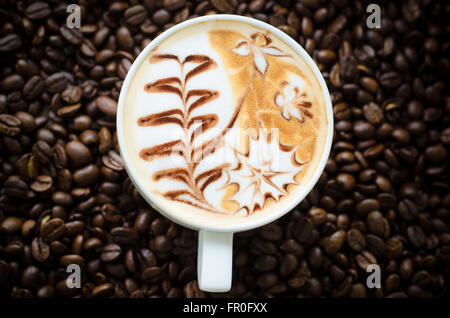 eine Tasse Latte Art on Kaffeebohne Hintergrund Stockfoto