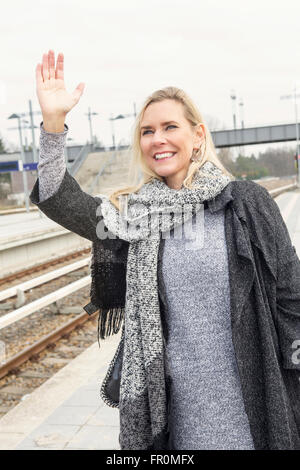 Porträt der blonden Frau am Bahnhof warten und jemanden begrüßen Stockfoto