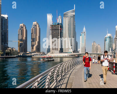 Menschen zu Fuß auf der Promenade mit Wasser Hochhäuser im Marina District von Dubai, Vereinigte Arabische Emirate Stockfoto