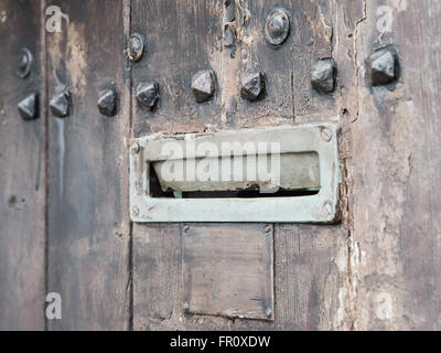 Alten rostigen Eisen Briefkasten öffnete am braunen Holztür mit Metallverzierungen, absichtlich verwischt. Stockfoto