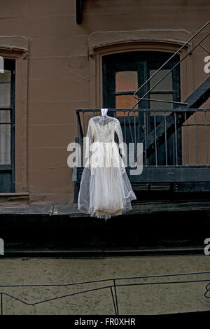 Ein weißes Hochzeitskleid hängt von einer Feuerleiter an 18th Street im Abschnitt Chelsea in Manhattan, New York City Stockfoto