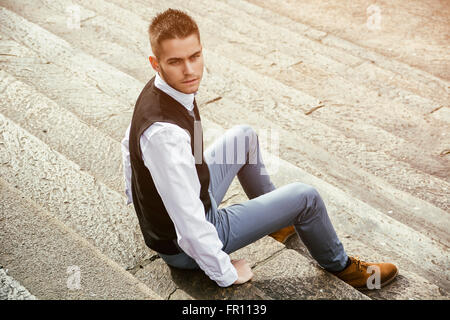 Hübscher junger Mann im Freien tragen Jacke und Hemd, die historischen Gebäude in europäischen Städten zu sitzen. Turin, Italien Stockfoto