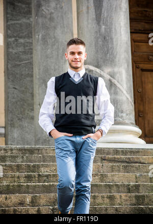 Hübscher junger Mann outdoor tragen Jacke und Hemd stehen durch die historischen Gebäude, Treppen hinunter in europäischen Städten. Turin, Stockfoto