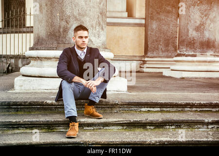 Hübscher junger Mann im Freien tragen Jacke und Hemd, die historischen Gebäude in europäischen Städten zu sitzen. Turin, Italien Stockfoto