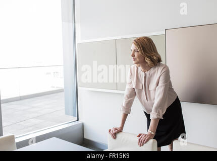 Nachdenklich schaut Bürofenster Geschäftsfrau Stockfoto