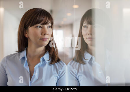 Nachdenklich schaut Bürofenster Geschäftsfrau Stockfoto