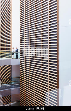 Geschäftsleute, die am Gehweg im modernen Büro Atrium sprechen Stockfoto