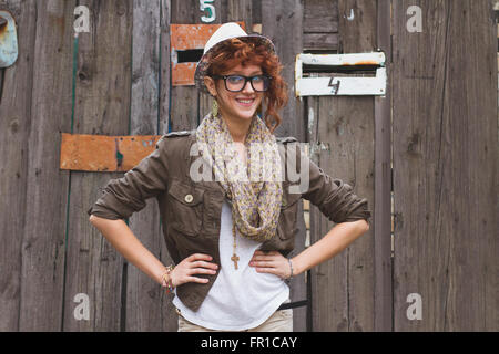 Cool aussehende junge Hipster Mädchen in Gläsern und Hut auf hölzernen Hintergrund. Stockfoto