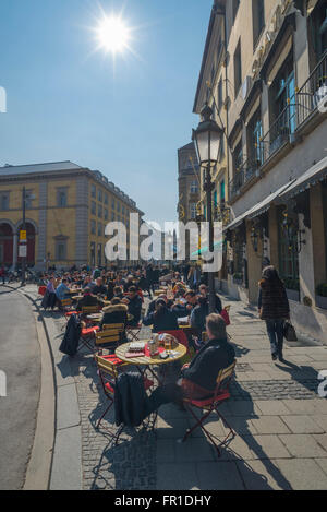 Gäste des historischen Gasthauses auf dem Max-Joseph-Platz in München genießen die Frühlingssonne für Mittagessen oder ein Getränk auf der Terrasse Stockfoto