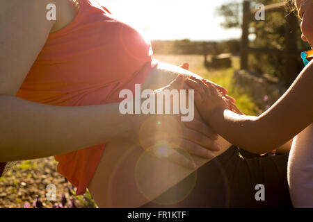 Schwangere Mutter und ihr kleiner Tochter erwarten Neugeborenen Bruder am Natur-Umwelt Stockfoto