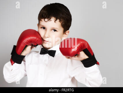 Fünf Jahre alter Junge in weißem Hemd und Fliege mit Boxingkarate Handschuhen an den Händen Stockfoto