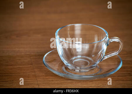 Glas Tasse und Untertasse auf Holztisch closeup Stockfoto