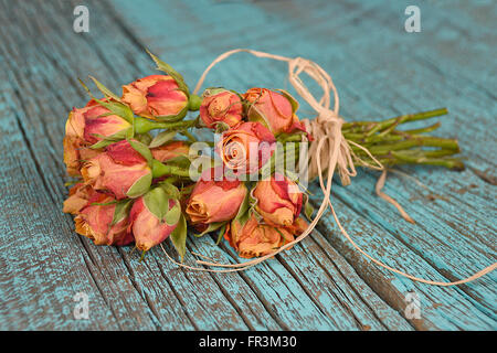 Orange rose Strauß gebunden mit Bast Bogen auf Aqua rustikale Holz lackiert. Stockfoto