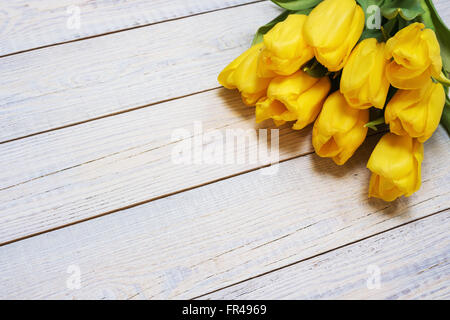 Frische gelbe Tulpen auf hölzernen Hintergrund. Urlaub-Hintergrund. Ansicht von oben. Stockfoto