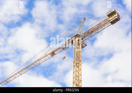 Gelbe Industriekran arbeitet auf Baustelle gegen blauen Himmel Stockfoto