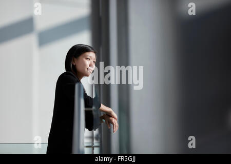 Nachdenklicher Blick durch sonnige Bürofenster Geschäftsfrau Stockfoto