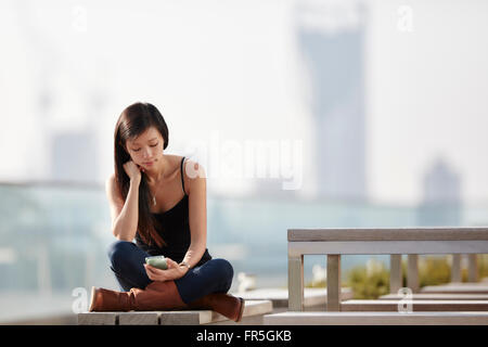 Frau SMS auf Bank im freien Stockfoto