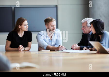 Geschäftsleute, die Papiere in Treffen diskutieren Stockfoto