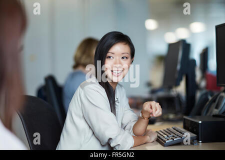 Lächelnde Geschäftsfrau im Gespräch mit Kollegen im Büro Stockfoto