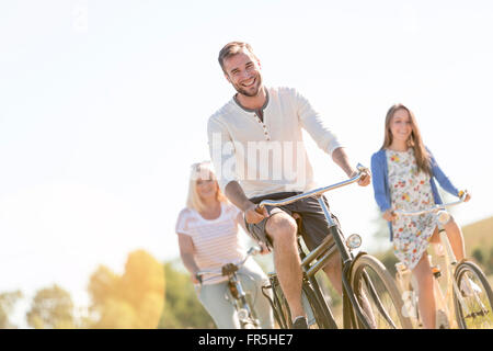 Lächelnd junger Mann Radfahren mit Frauen Stockfoto