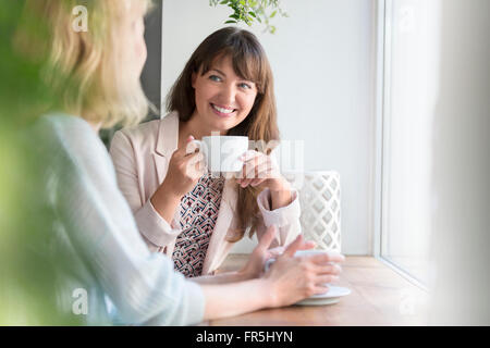 Lächelnde Frauen trinken Kaffee im Café Fenster Stockfoto