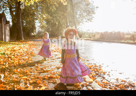 Kleinkind Mädchen in Halloween-Kostümen zu Fuß im Herbstlaub Stockfoto