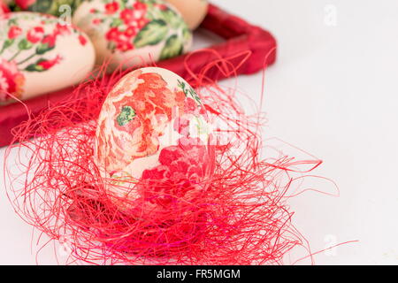 Serviettentechnik dekoriert Easter Egg auf roten Stroh Stockfoto