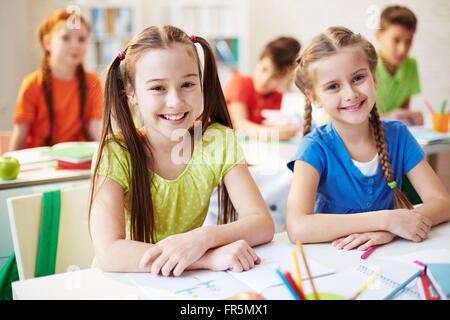 Porträt von zwei Schülerinnen und Schüler am Schreibtisch und lächelt in die Kamera Stockfoto