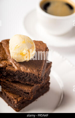 Brownie mit Eis und einer Tasse Kaffee auf dem Tisch vertikal Stockfoto