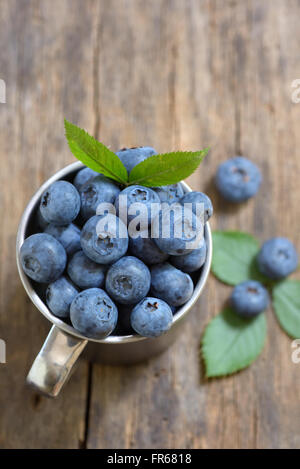 Frische Heidelbeeren in kleinen Tasse auf hölzernen Hintergrund Stockfoto