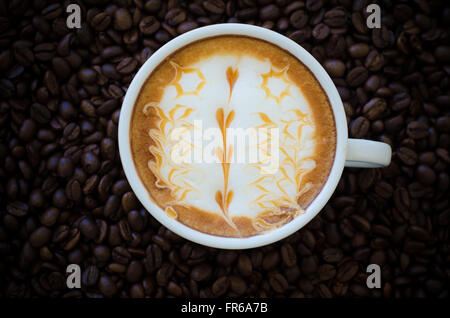 eine Tasse Latte Art on Kaffeebohne Hintergrund Stockfoto