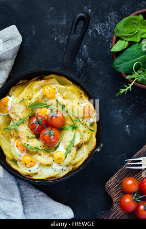 Frühstück Kartoffel Frittata mit Spinat, Cherry-Tomaten und Käse in der Pfanne. Tabelle Draufsicht auf schwarzem Hintergrund. Still-Leben Stockfoto