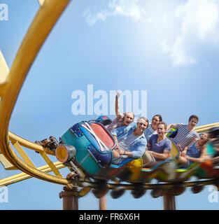 Jubelnde Freunde fahren Achterbahn im Freizeitpark Stockfoto