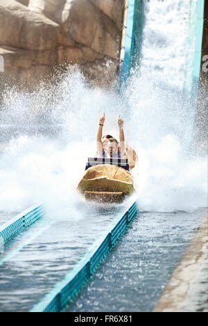 Begeisterter junger Mann Reiten Wildwasserbahn Log Vergnügungspark Stockfoto