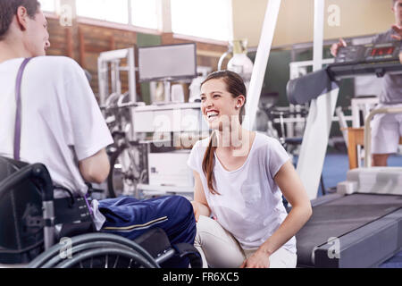 Lächelnde Physiotherapeut Gespräch mit Mann im Rollstuhl Stockfoto