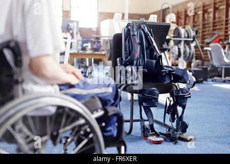 Mann im Rollstuhl in der Nähe von Physiotherapie-Ausrüstung Stockfoto