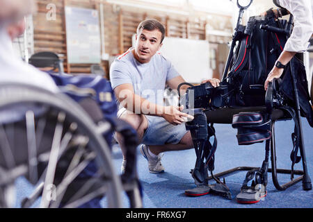 Physiotherapeut erklärt Ausrüstung Mann im Rollstuhl Stockfoto