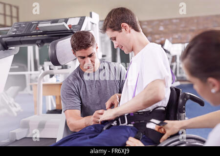 Physiotherapeuten, die Mann im Rollstuhl Geräte zuweisen Stockfoto