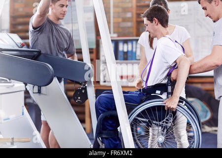 Physiotherapeuten helfen Mann im Rollstuhl auf Laufband Stockfoto