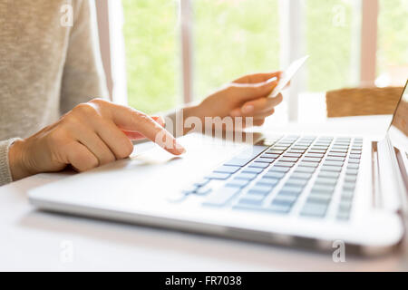 Frau zu Hause mittels Kreditkarte und Laptop. Online-Shopping Stockfoto
