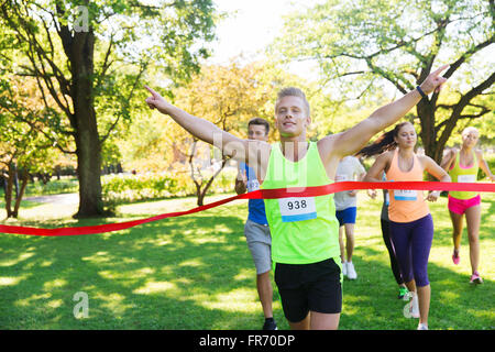 glückliche junge männliche Läufer gewinnen auf Rennen beenden Stockfoto