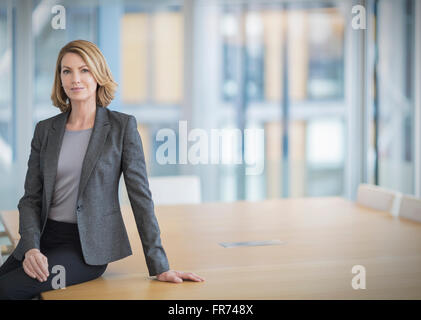 Porträt zuversichtlich Geschäftsfrau stützte sich auf Konferenztisch Stockfoto