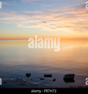 Hellen und farbenfrohen Sonnenuntergang von einer Küste mit ruhigem Wasser Stockfoto