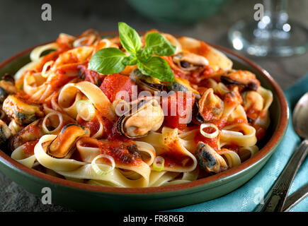 Leckere Pasta mit Muscheln in Basilikumsauce marinara. Stockfoto