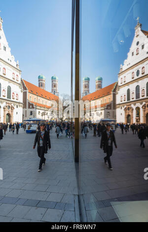 Junger Mann sieht in einem Shop Eingang in die Fußgängerzone von München symmetrisch gespiegelten im Schaufenster Stockfoto