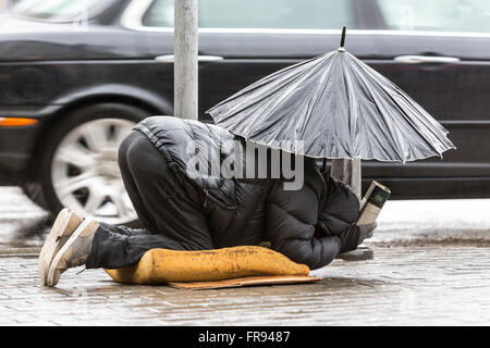 Obdachlose Bettler ist betteln um Geld in eine Hauptstraße in Sofia hält einen Regenschirm an einem regnerischen Tag. Bulgarien ist die Anzahl der ärmsten Stockfoto